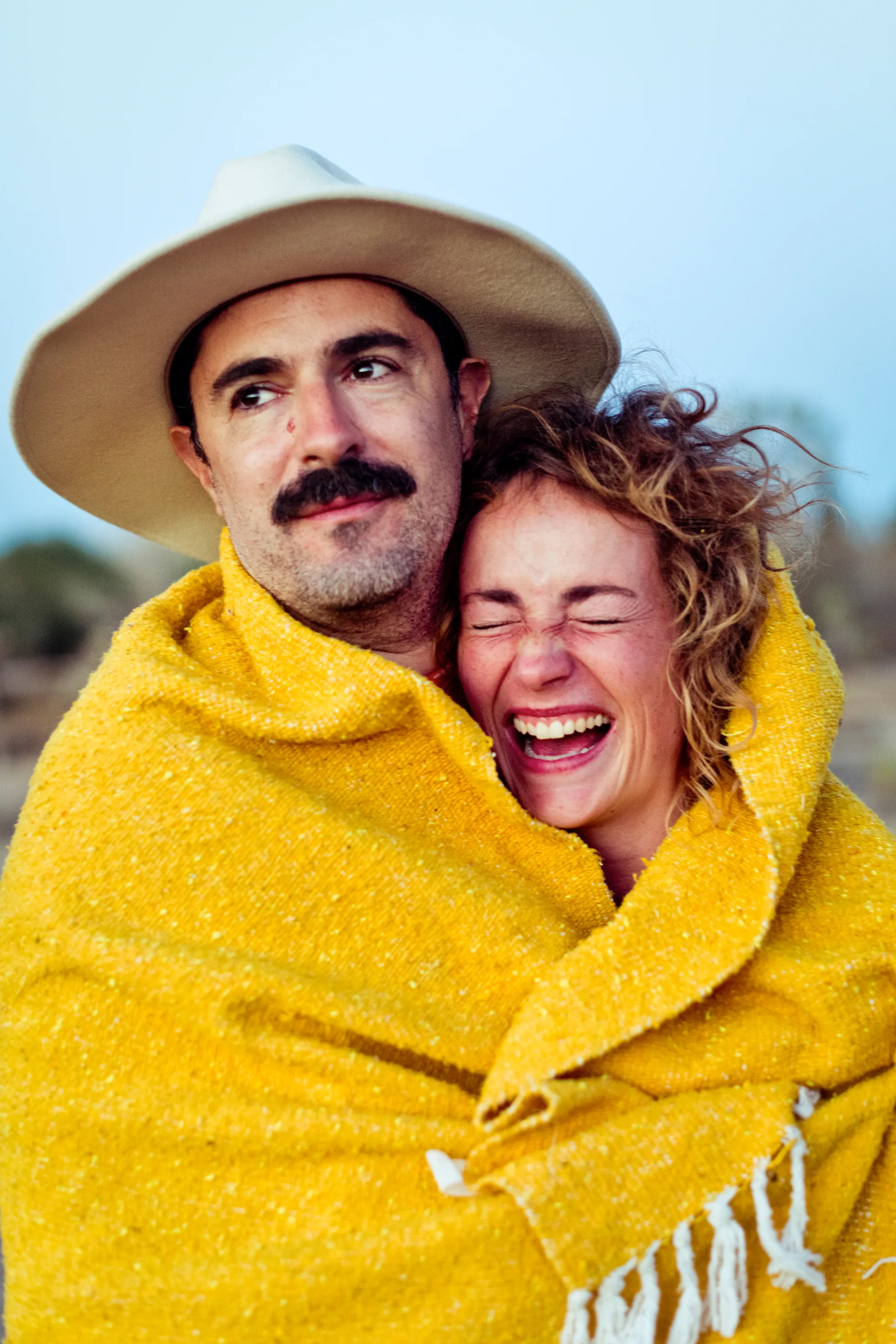 Two Grow Therapy clients wrapped in a blanket, laughing together