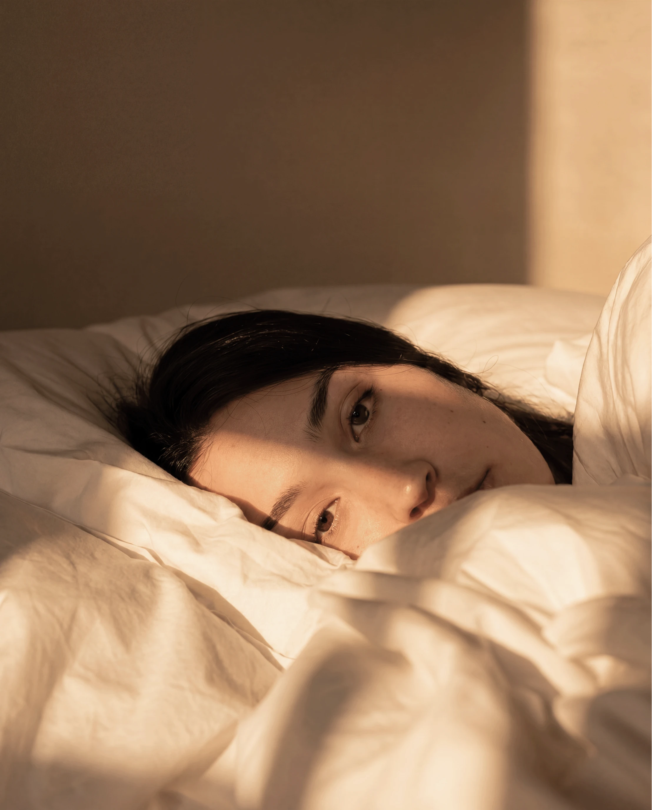 A Grow Therapy client lying in bed in warm morning light