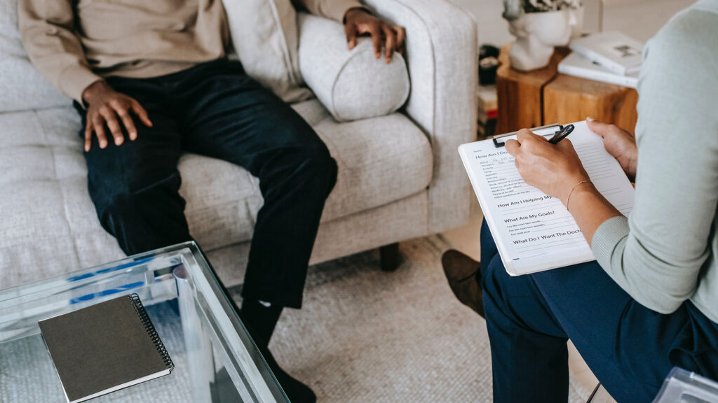 An image of two people sitting on opposite couches in a therapy session.