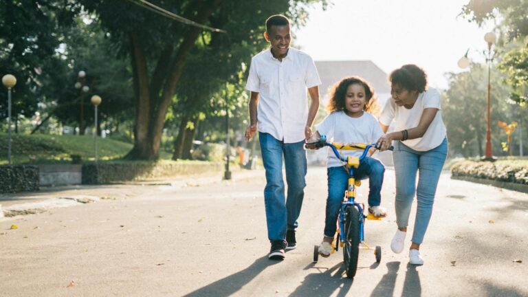 Happy parents teaching their child to ride a bike