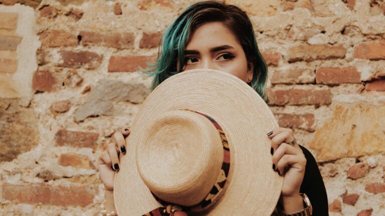 Woman hides her face with a hat.