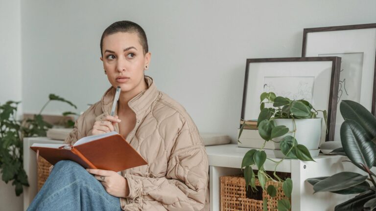 Woman reflects while journaling.