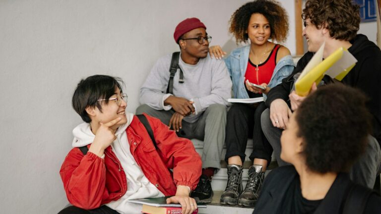 A group of teenagers sit in the stairwell of their school, chatting between classes.