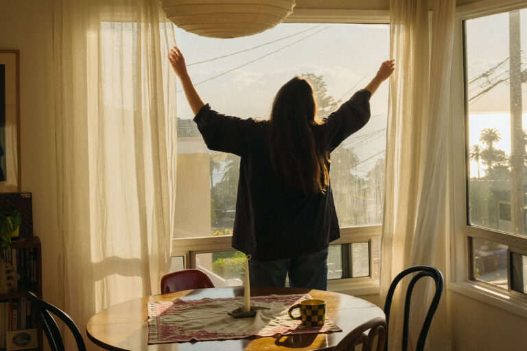 Person looking out the window with open arms.