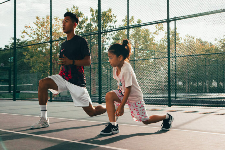 A child and teacher on a tennis court